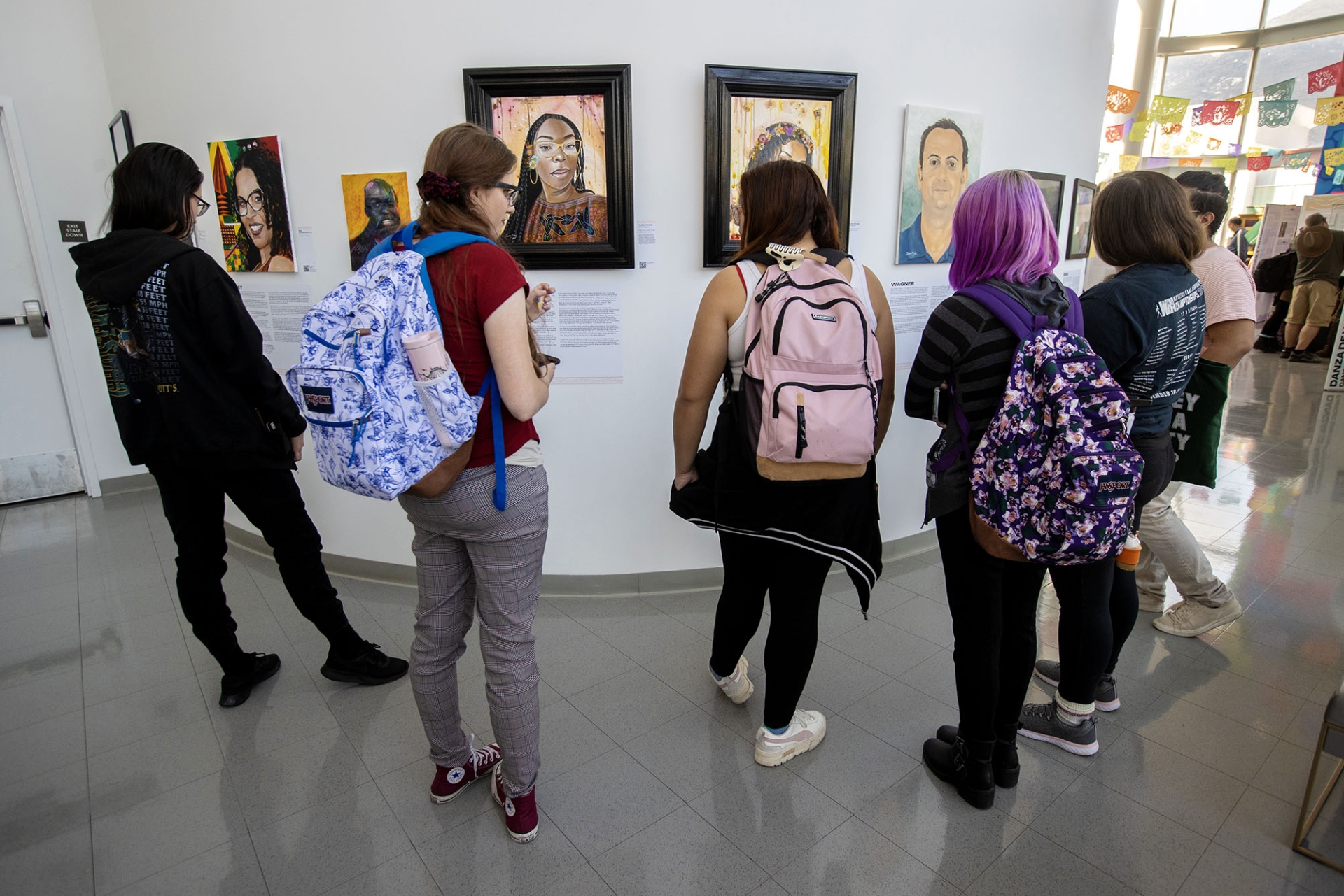 Visitors look over some of the 21 portraits and biographies of Afrolatine Californians at the Afróntalo exhibit at the CSUSB Anthropology Museum.