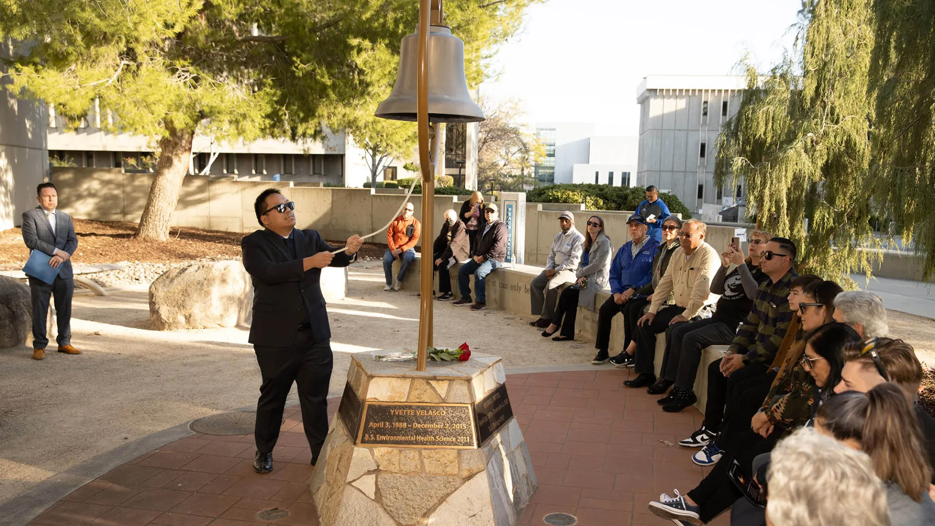 Michael Nguyen, a former faculty member in the Department of Health Science and Human Ecology, rings the bell at Cal State San Bernardino’s Peace Garden during the 2023 Day of Remembrance. 