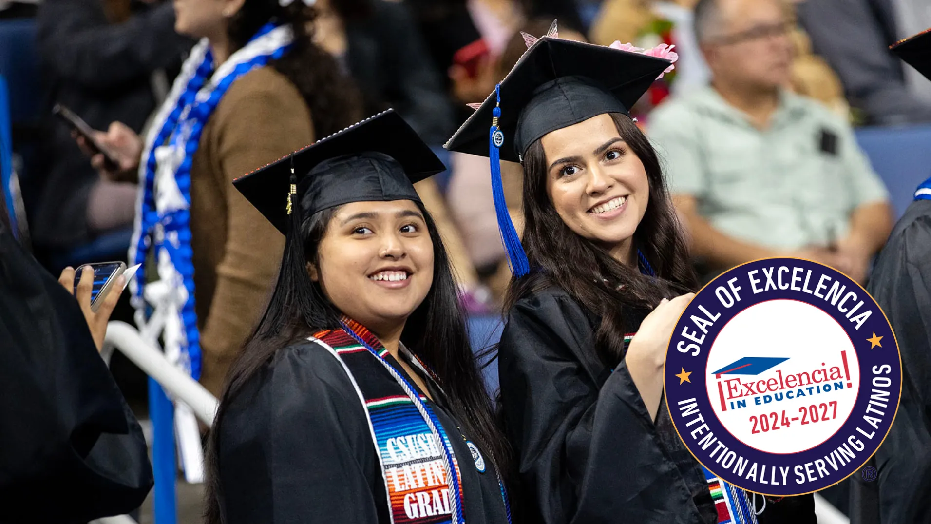 Two Cal State San Bernardino graduates at the university’s 2022 spring Commencement; the Seal of Excelencia is superimposed over the image.