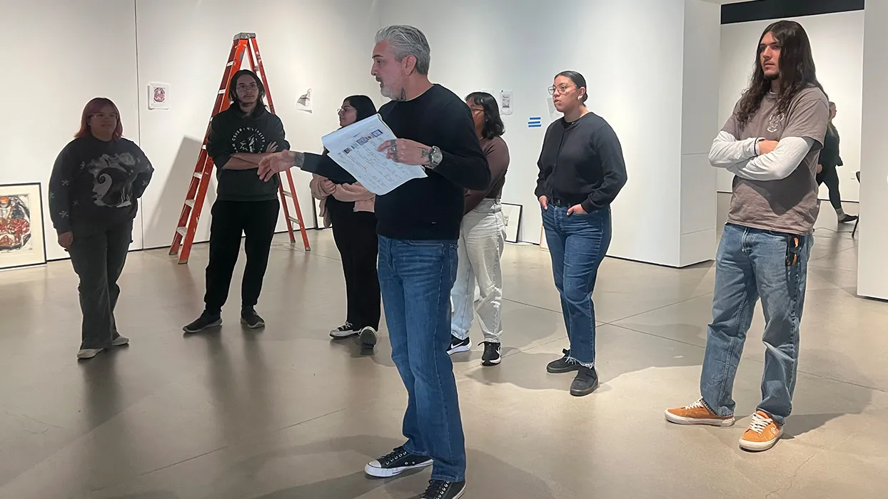 The Robert and Frances Fullerton Museum of Art staff and students discuss an exhibit in the museum gallery.