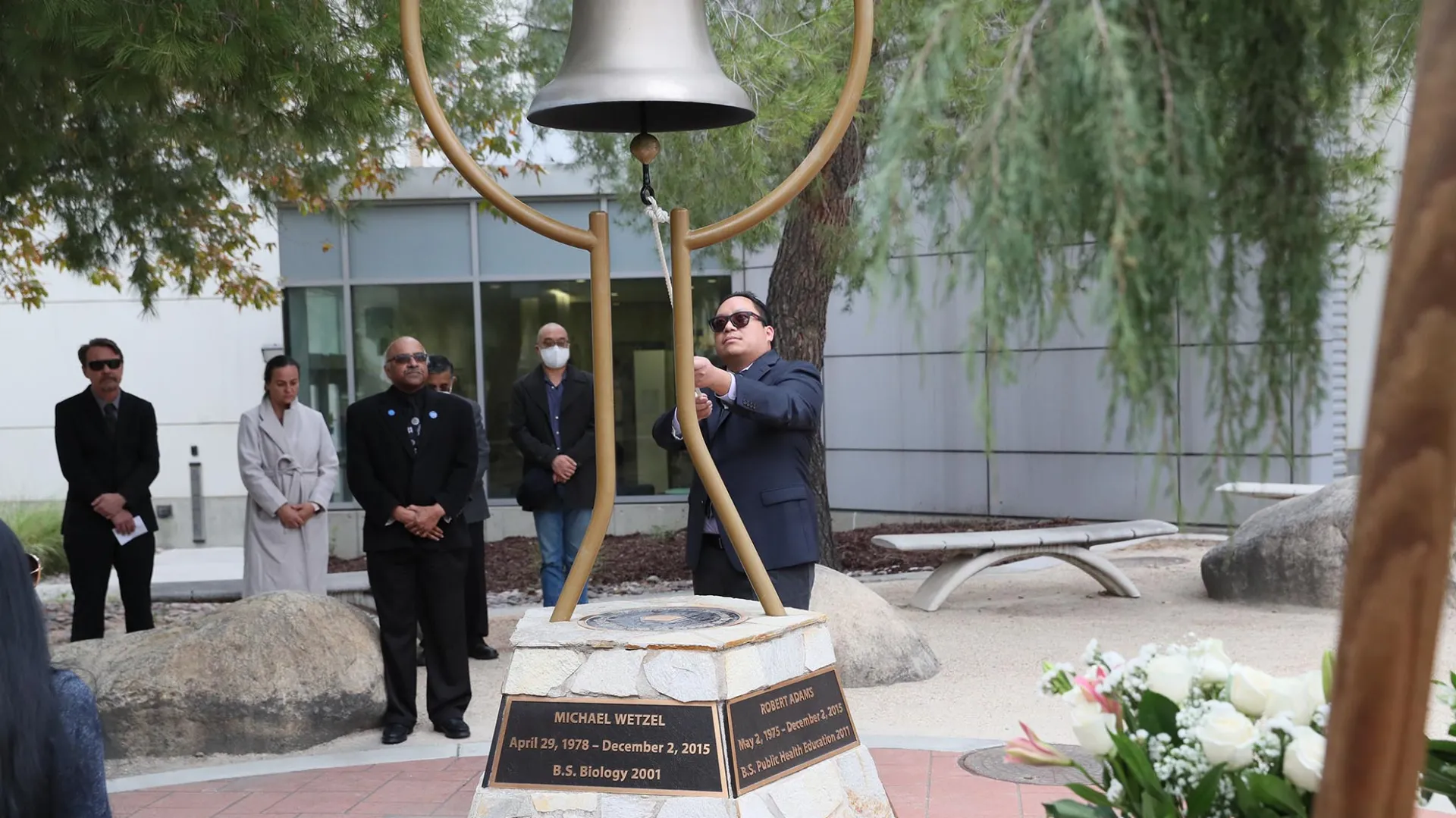 Michael Nguyen, a former faculty member in the Department of Health Science and Human Ecology, rings the bell at the Peace Garden on the Day of Remembrance, Dec. 2.