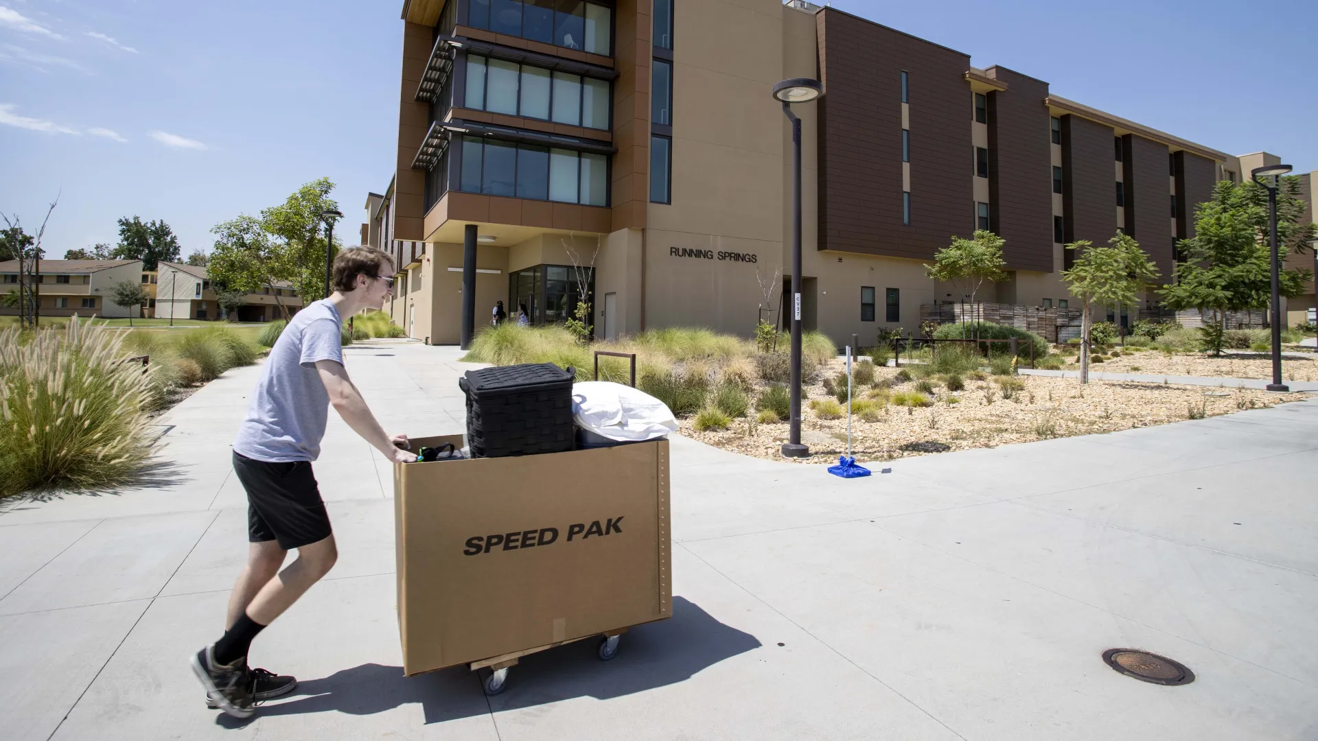 A student pushes a cart of his belongings as he makes his way to his on-campus home during Move-In days.