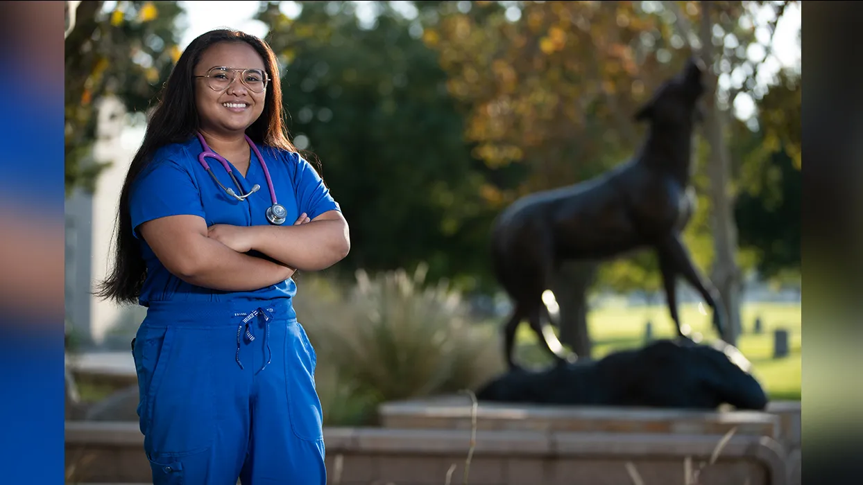 Nursing student standing by the Wild Song statue at CSUSB