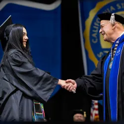 CSUSB President Tomás D. Morales congratulates a member of the Class of 2024 at the College of Social and Behavioral Sciences Commencement ceremony on May 17.