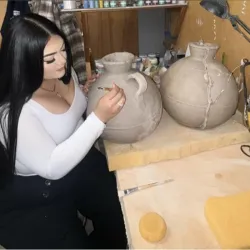 Master of Fine Arts student, Katherine Yvonne Posada, working in their studio, shaping a ceramic vessel that will be part of her thesis exhibition at RAFFMA.