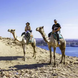 Nathaniel Saavedra, at right, with another person, both on camels in Egypt.