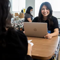 CSUSB student smiling while working on lap top computer