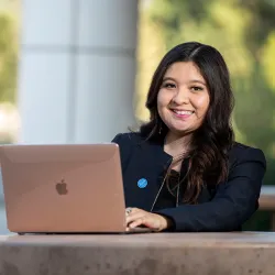 A student in front of Jack Brown Hall using her laptop 