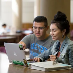 Two students working on a laptop