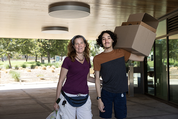 A student carries boxes as he heads to his on-campus home during move-in days.