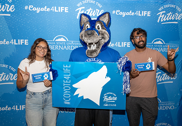 Two students receive their “Coyote Pass,” which ensures pre-approval or an admissions seat for the spring 2025 semester at Cal State San Bernardino. 