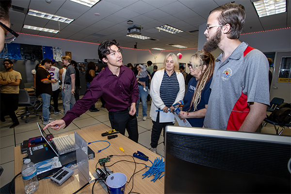 A student discusses his project with open house attendees.