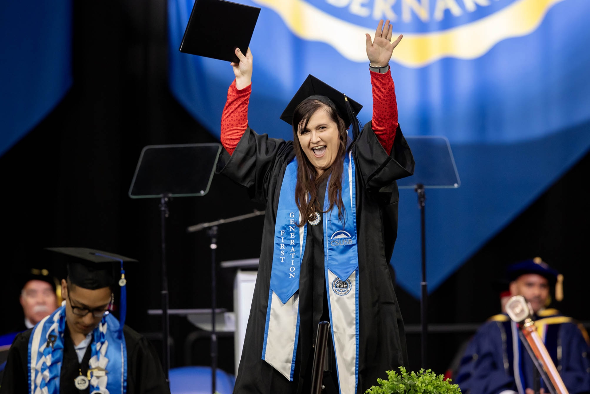 A student wearing a First Generation sash celebrates as she crosses the stage during the Jack H. Brown College of Business and Public Administration commencement on May 17.