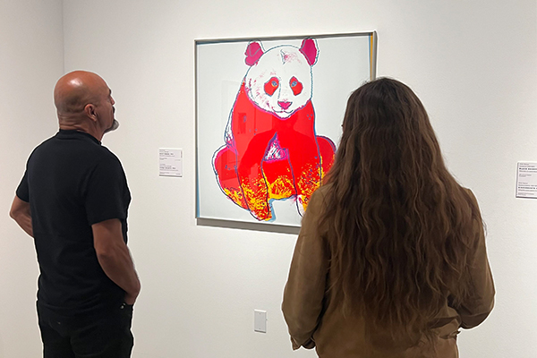Attendees contemplate artwork displayed at a RAFFMA exhibition.