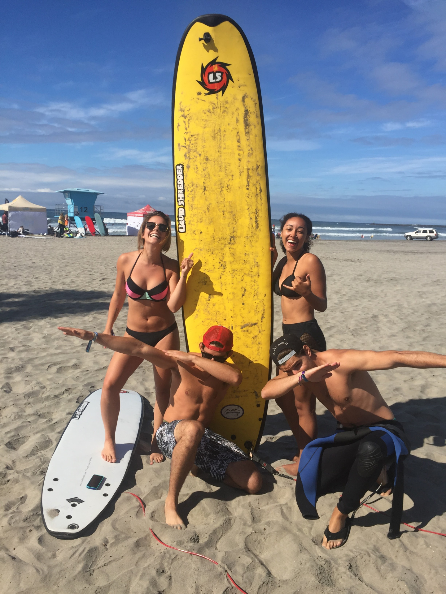 4 people posing by surfboard