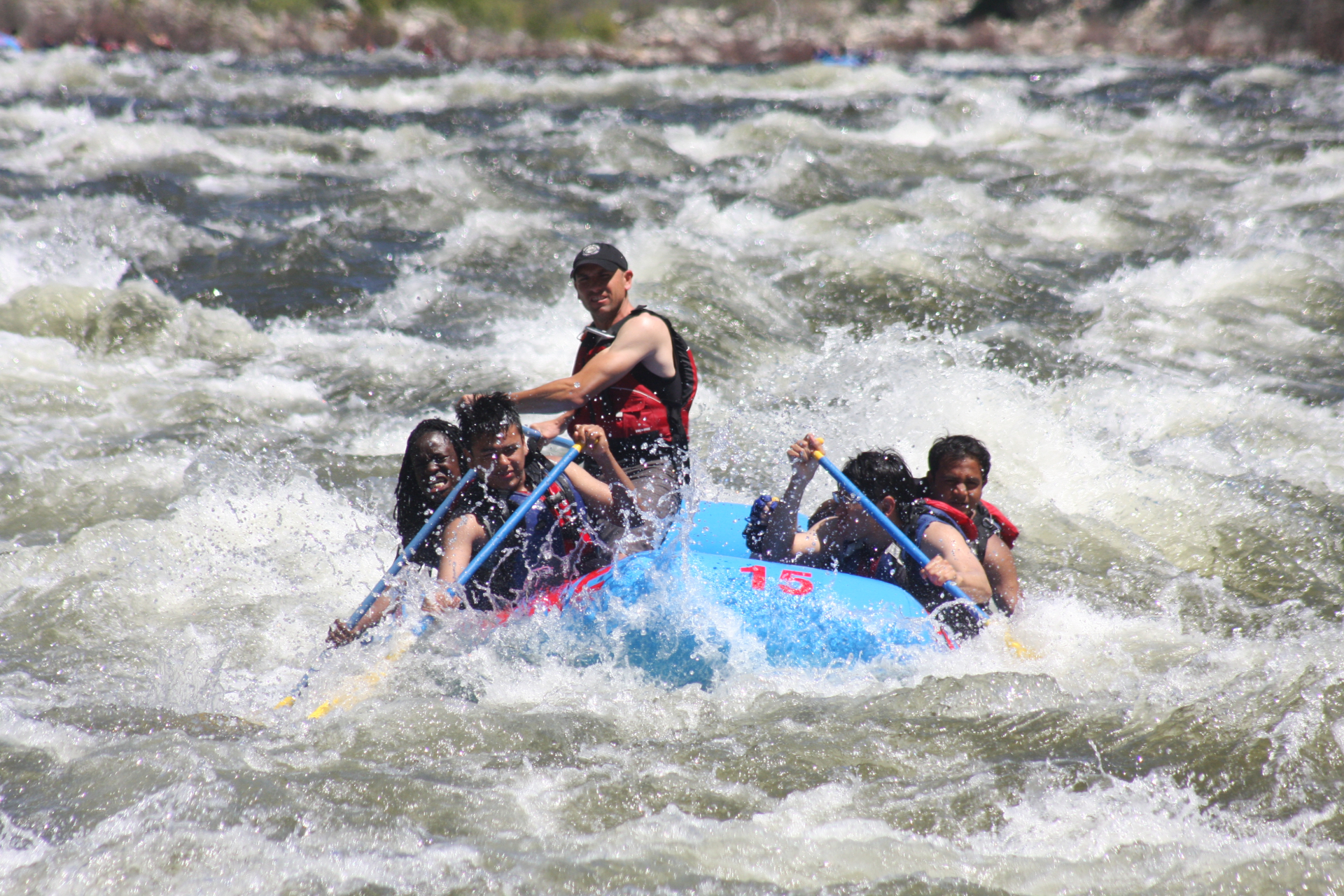 rafter going down rapid in blue boat