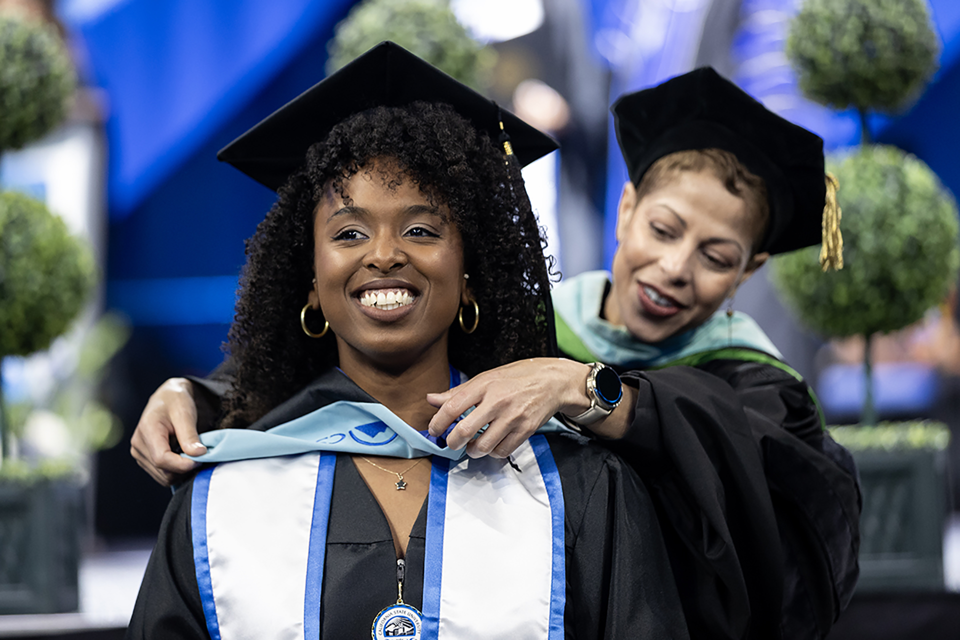 A graduate receives her master's hood from a faculty member.