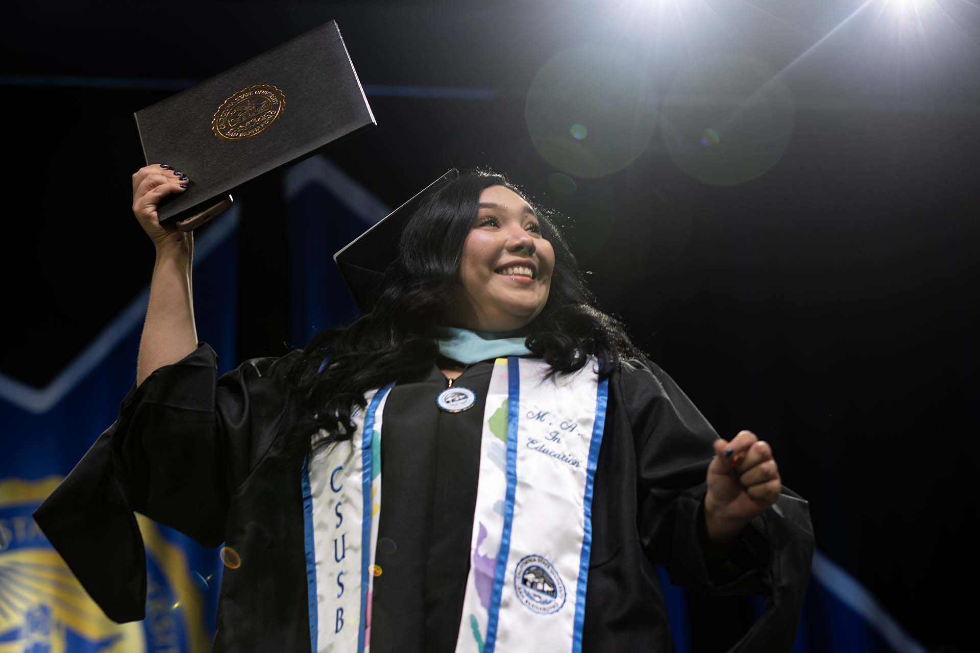 A member of the Class of 2026 raises her diploma cover in celebration.